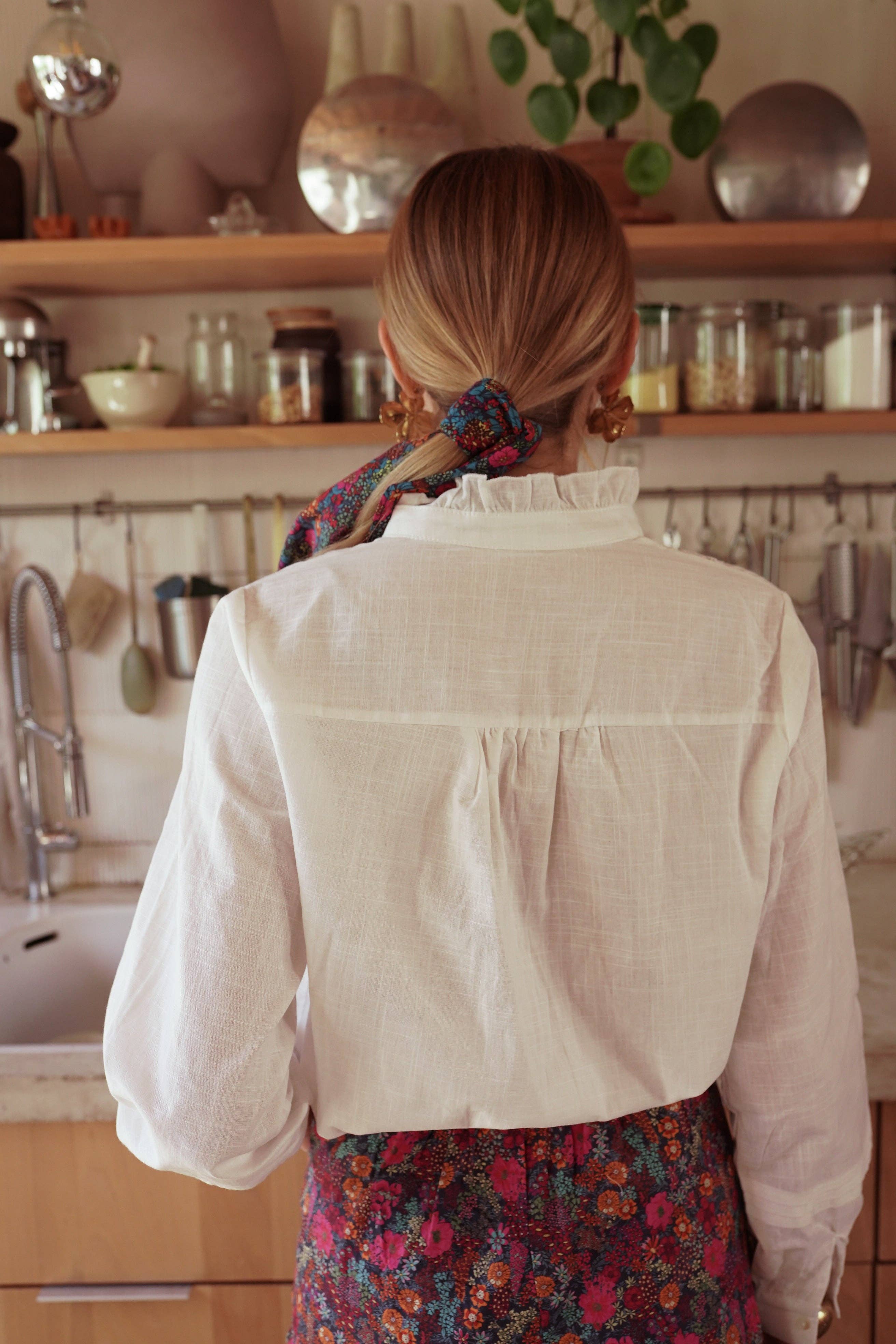Blusa blanca de cuello alto con pliegues trabajados